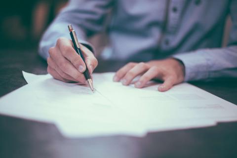 a Person writing on paper to represent the importance of having a will