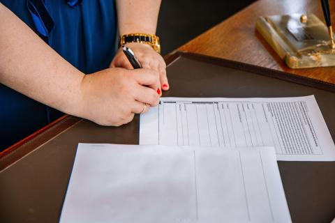 A woman signing documents to represent "what is a notary public?"