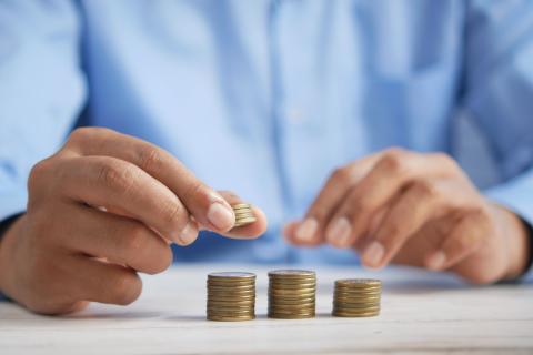 A person stacking coins to represent the debt collection process